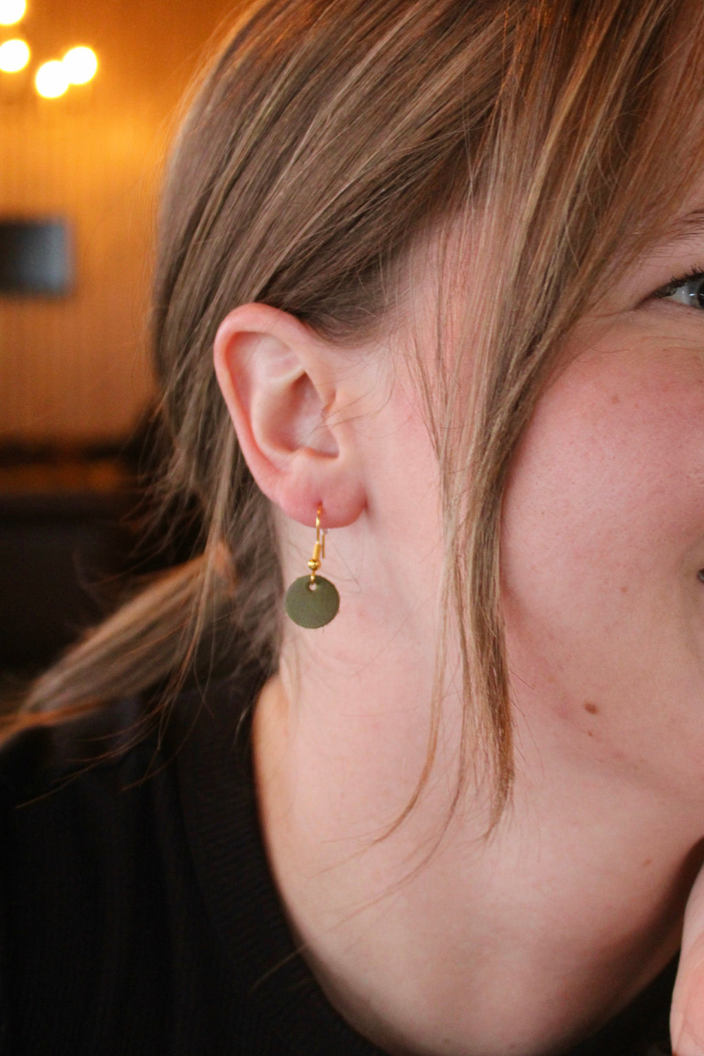 Model wearing Georgie Bee tiny leather moon earrings in olive green