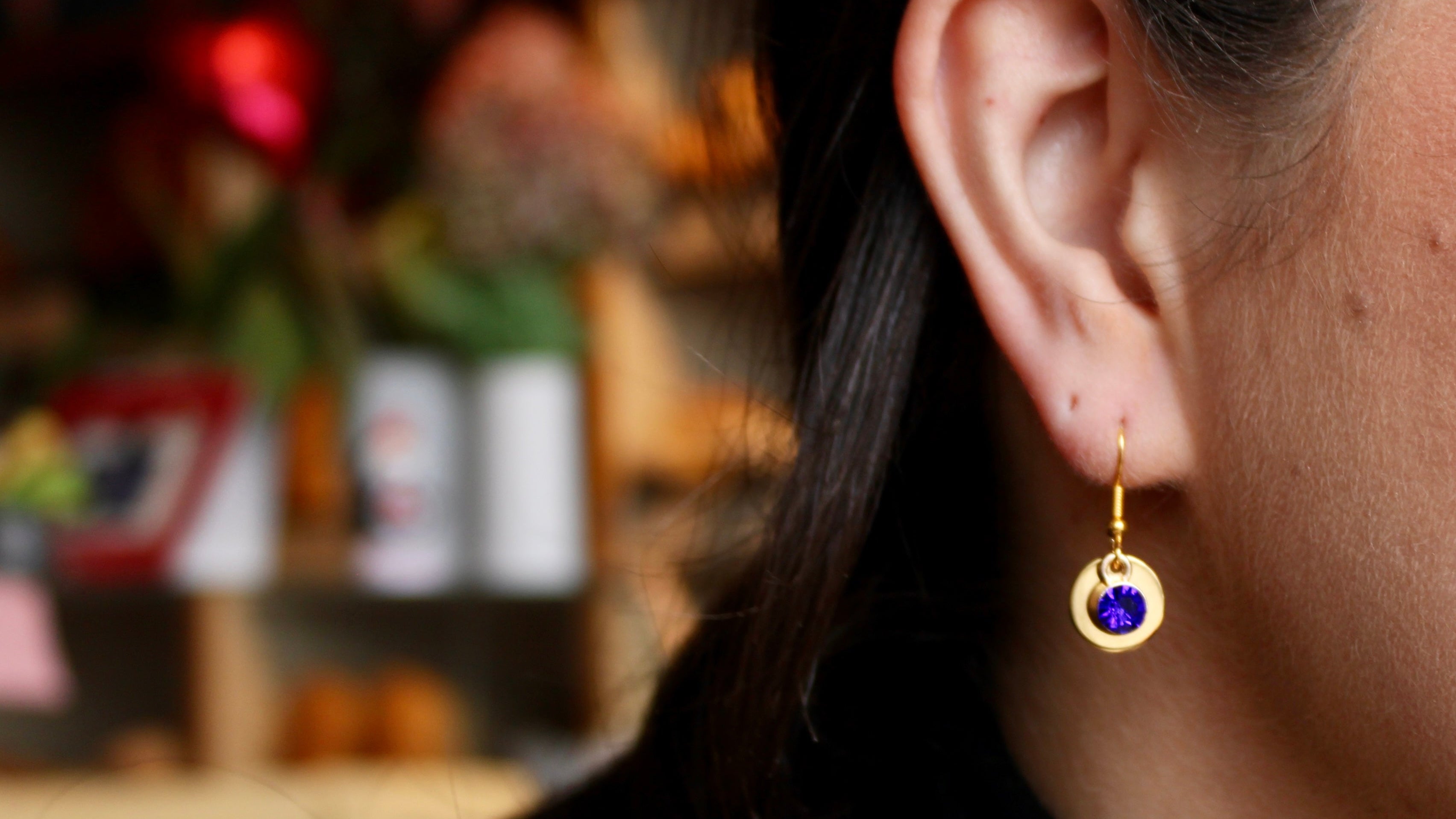 Close-up of a woman wearing gold earrings with a dark background
