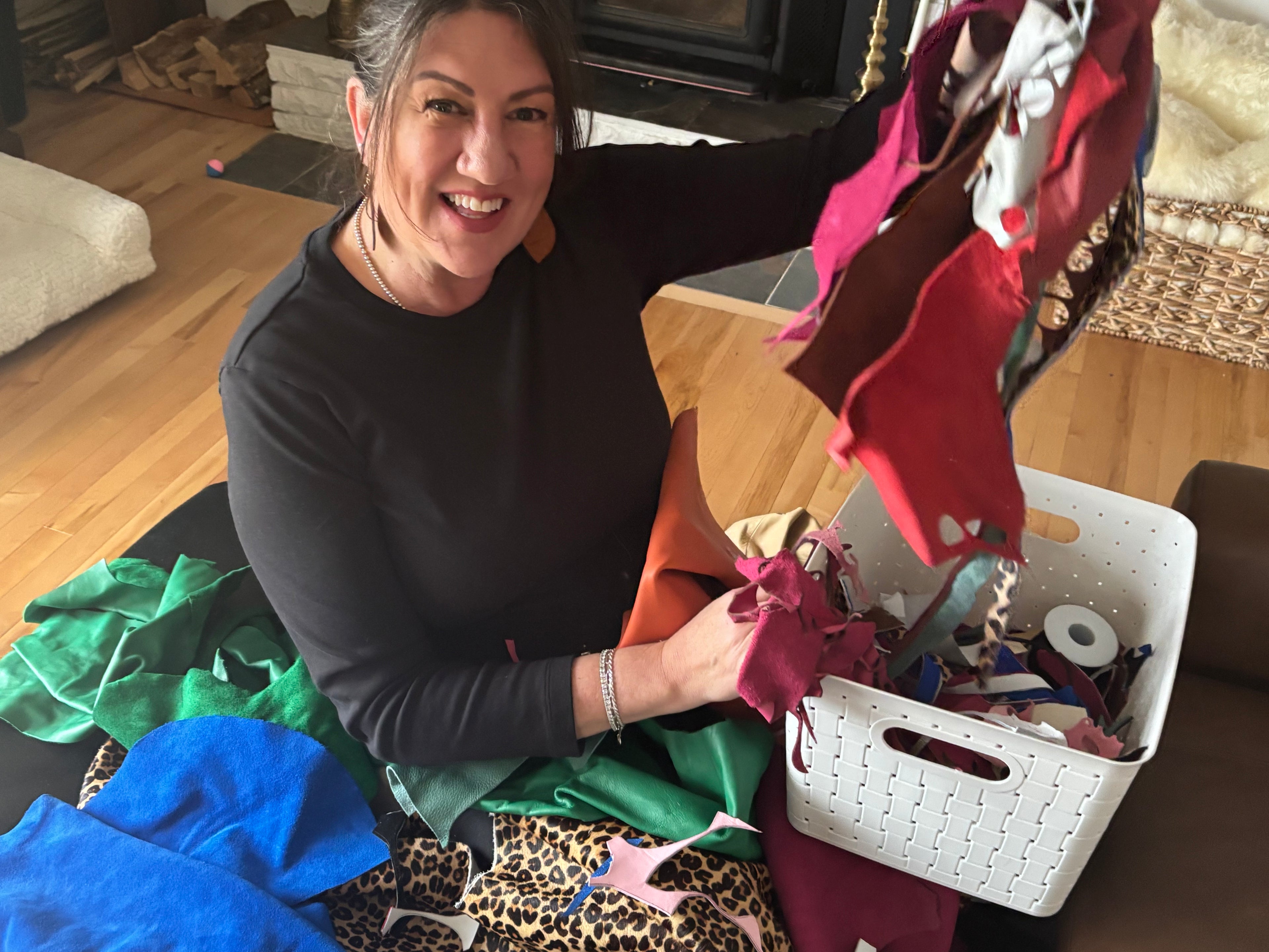 founder of bee&sallie handcrafted jewelry in a pile of leather smiling