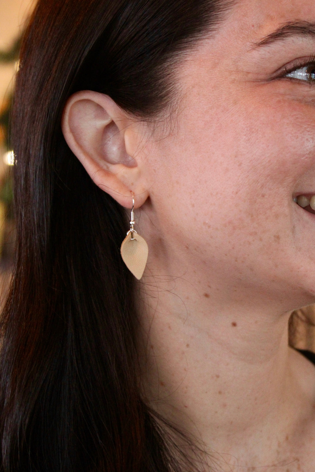 Model wearing Lexy Bee tiny leather petal earrings in tan